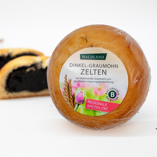 Der runde Dinkel-Graumohnzelten, in transparenter Folie verpackt liegt auf weißem Untergrund, umgeben von verstreuten Mohnsamen. Auf der Verpackung befindet sich ein Etikett mit der Aufschrift "Waldland Dinkel-Graumohnzelten – regionale Spezialität" sowie einer Abbildung von aufblühenden rosa Mohnblüten und einer Dinkelähre. Im Hintergrund sind angeschnittene Dinkel-Graumohnzelten, wo die saftige Füllung zu sehen ist.