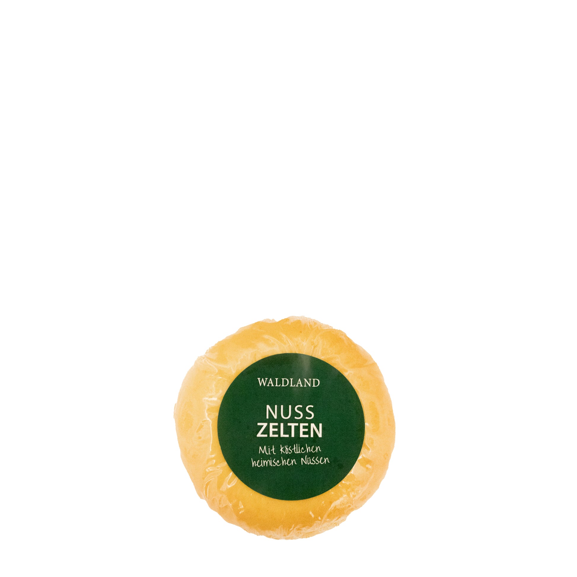 Der runde Nusszelten, in transparenter Folie verpackt liegt auf weißem Untergrund. Auf der Verpackung befindet sich ein dunkelgrünes Etikett mit weißer Aufschrift "Waldland Nusszelten – mit köstlichen heimischen Nüssen". Im Hintergrund sind angeschnittene Nusszelten, wo die saftige Füllung zu sehen ist.
