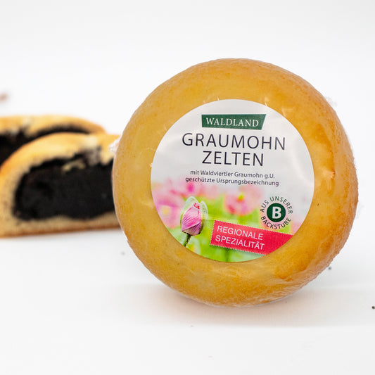 Der runde Graumohnzelten, in transparenter Folie verpackt liegt auf weißem Untergrund, umgeben von verstreuten Mohnsamen. Auf der Verpackung befindet sich ein Etikett mit der Aufschrift "Waldland Graumohnzelten – regionale Spezialität" sowie einer Abbildung von aufblühenden rosa Mohnblüten. Im Hintergrund sind angeschnittene Graumohnzelten, wo die saftige Füllung zu sehen ist.